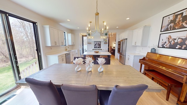 dining room with sink, a notable chandelier, and light hardwood / wood-style flooring