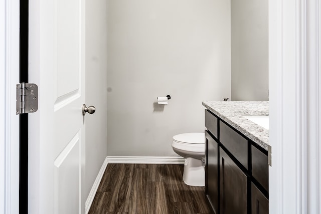 bathroom with toilet, baseboards, wood finished floors, and vanity