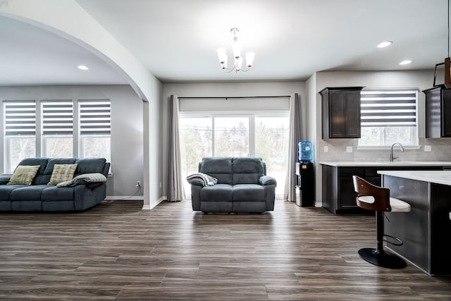 living area with arched walkways, a chandelier, recessed lighting, baseboards, and dark wood-style floors