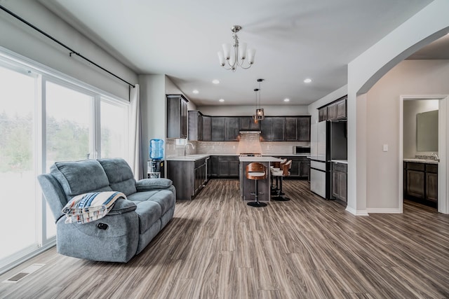 interior space with light countertops, backsplash, freestanding refrigerator, open floor plan, and dark brown cabinets