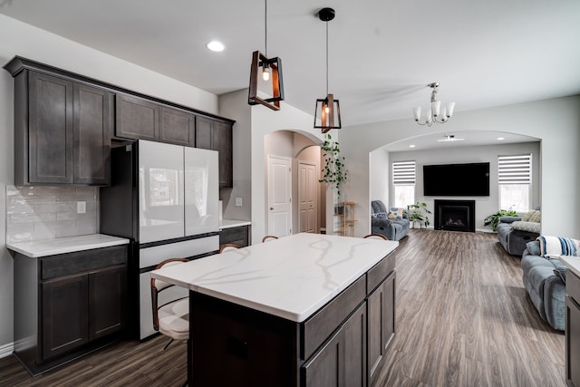 kitchen featuring open floor plan, dark brown cabinetry, freestanding refrigerator, and decorative light fixtures