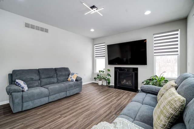 living area with recessed lighting, wood finished floors, visible vents, baseboards, and a glass covered fireplace