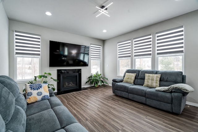 living room featuring a fireplace with flush hearth, baseboards, wood finished floors, and recessed lighting