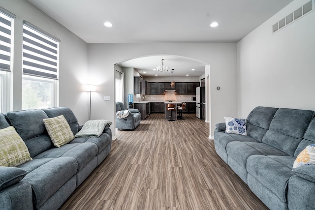 living room with dark wood-type flooring, recessed lighting, visible vents, and a notable chandelier