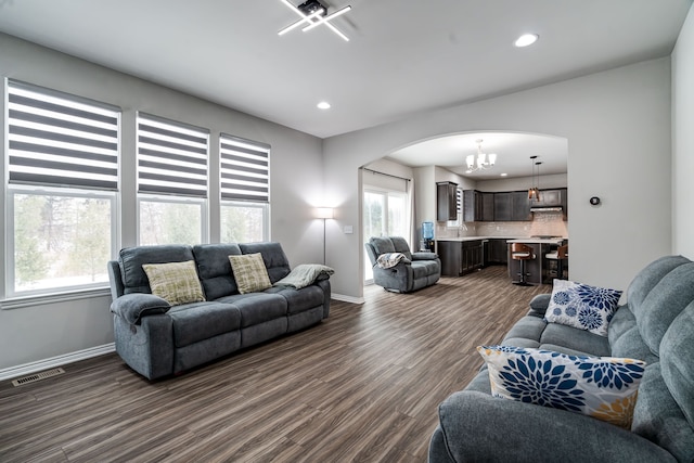 living area with visible vents, arched walkways, dark wood finished floors, baseboards, and recessed lighting