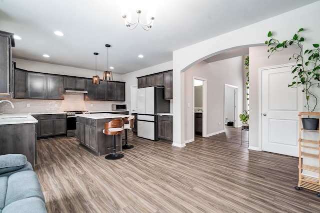 kitchen with a sink, stainless steel range oven, light countertops, freestanding refrigerator, and a center island