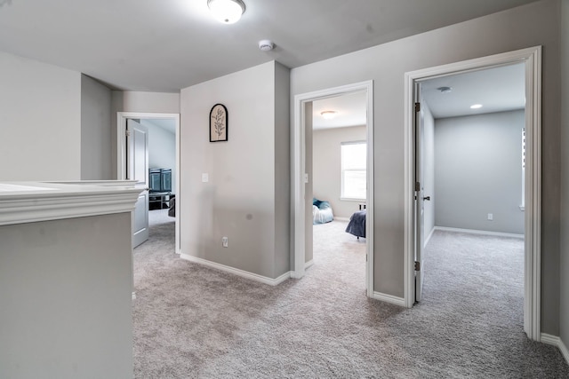 hall featuring light carpet and baseboards