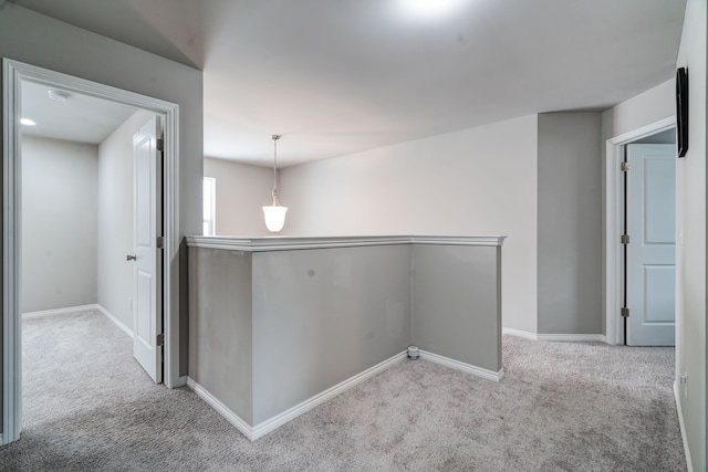 hallway featuring light carpet, baseboards, and an upstairs landing