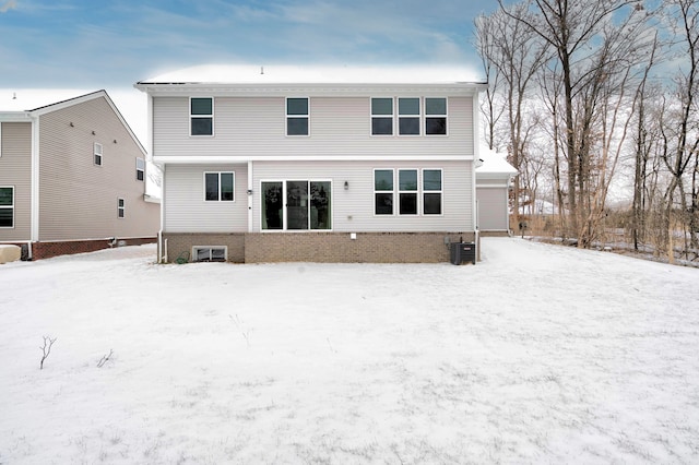 snow covered rear of property featuring central AC unit