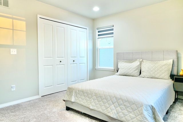 bedroom featuring baseboards, visible vents, a closet, and light colored carpet