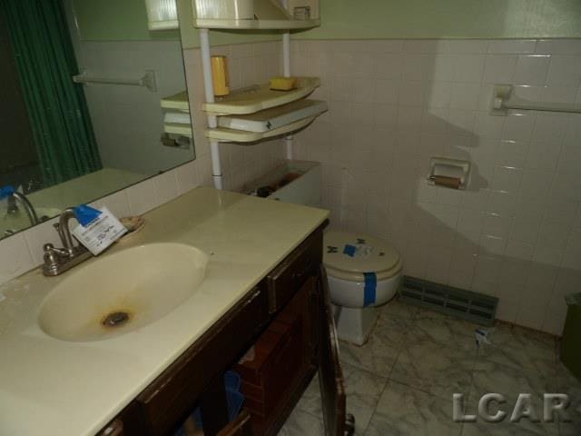 bathroom featuring vanity, tile walls, and toilet