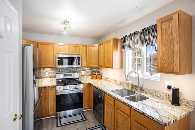 kitchen with stainless steel appliances, sink, tasteful backsplash, light stone counters, and dark hardwood / wood-style floors