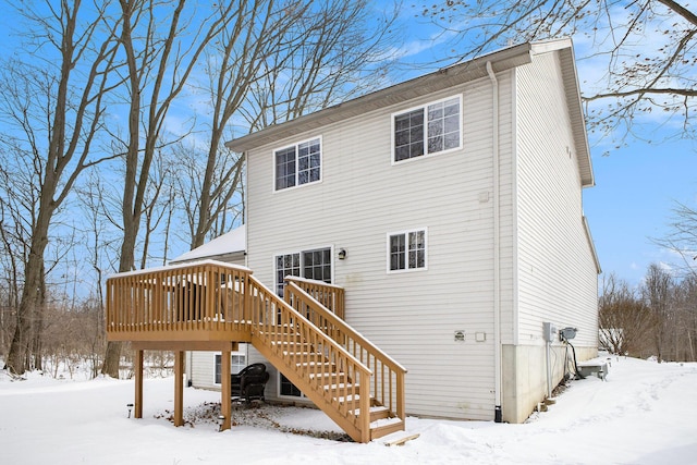 snow covered back of property featuring a deck