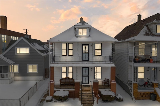 back house at dusk featuring covered porch