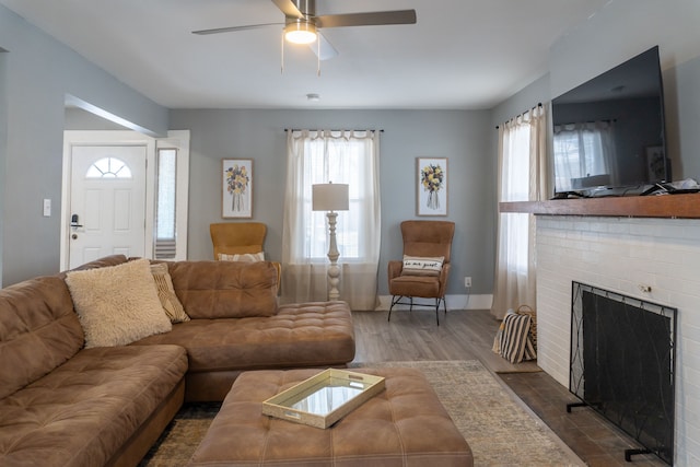 living area with a fireplace, ceiling fan, baseboards, and dark wood finished floors