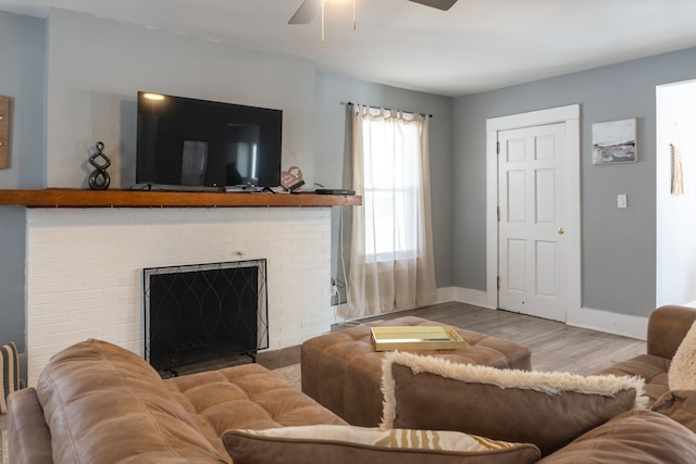 living room featuring a fireplace, a ceiling fan, baseboards, and wood finished floors