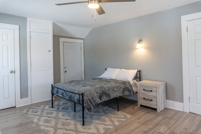 bedroom featuring baseboards, vaulted ceiling, light wood finished floors, and ceiling fan