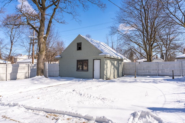 snow covered garage featuring fence