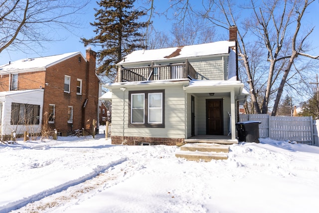 view of front of house featuring a balcony, a chimney, and fence