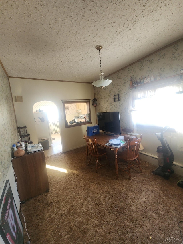 dining area featuring ornamental molding, dark carpet, a textured ceiling, and wallpapered walls