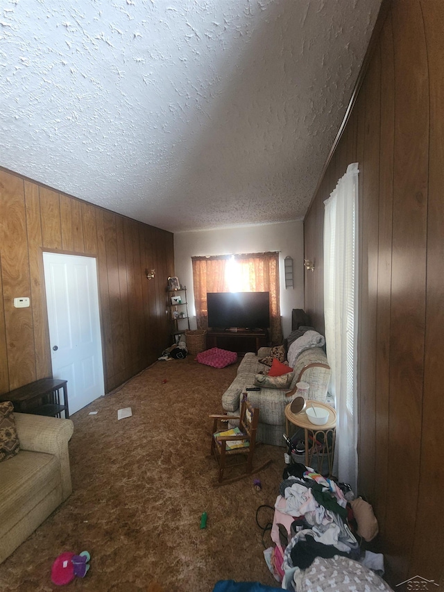 living area with lofted ceiling, carpet flooring, wood walls, and a textured ceiling