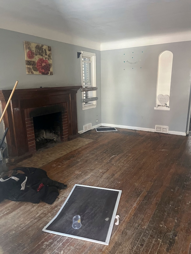 living room featuring a brick fireplace and wood-type flooring