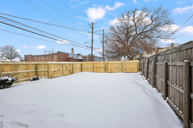 snowy yard featuring a fenced backyard