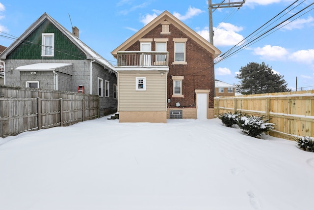 snow covered house featuring fence and brick siding