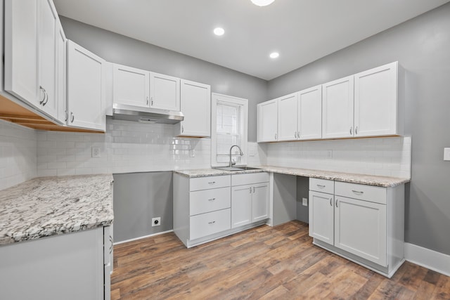 kitchen featuring light stone counters, dark wood finished floors, white cabinets, and under cabinet range hood