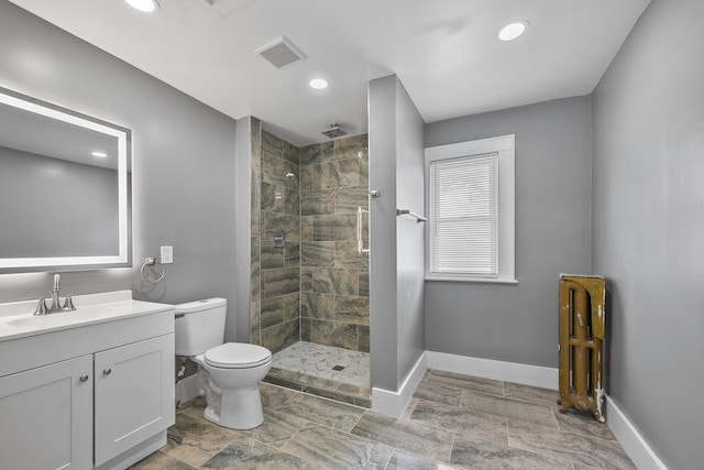 bathroom with visible vents, toilet, vanity, tiled shower, and baseboards