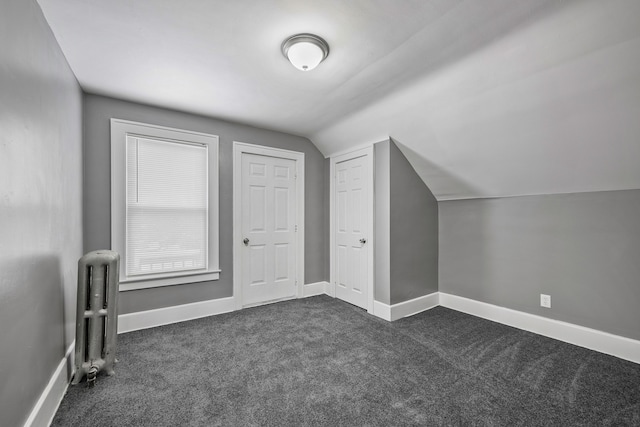 bonus room with radiator heating unit, vaulted ceiling, dark carpet, and baseboards