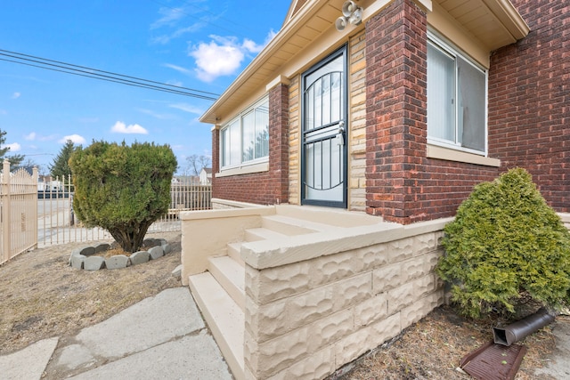 doorway to property with brick siding and fence