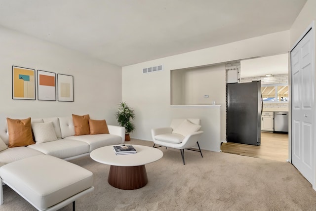 living area featuring visible vents and light carpet