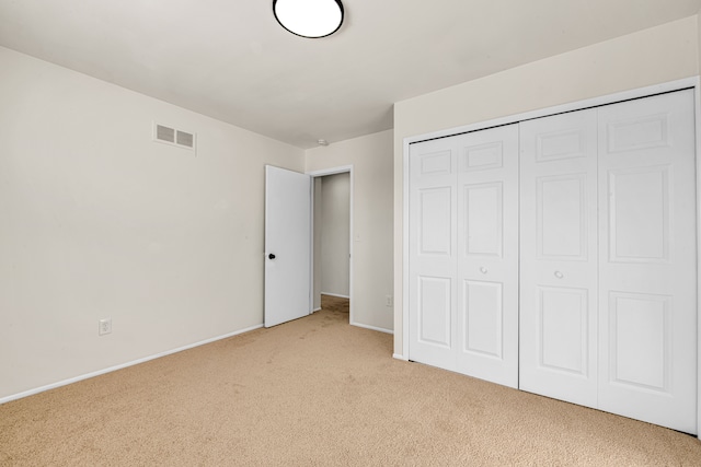 unfurnished bedroom featuring light colored carpet, a closet, visible vents, and baseboards