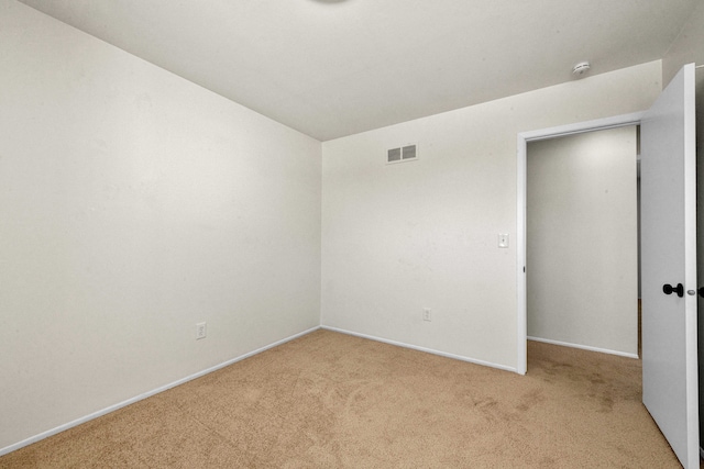 spare room with baseboards, visible vents, and light colored carpet