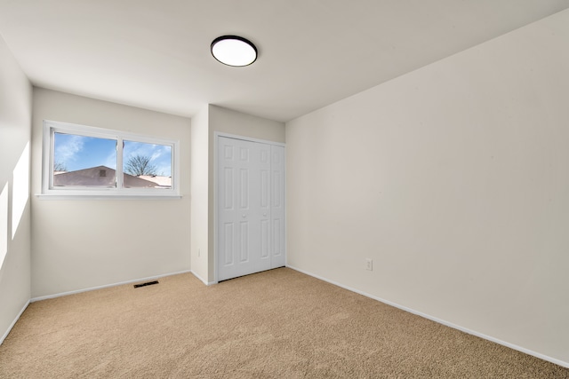 unfurnished bedroom with light carpet, baseboards, visible vents, and a closet