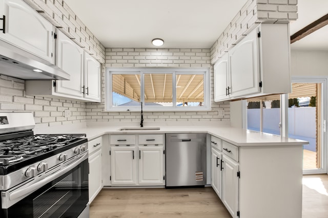 kitchen with light countertops, appliances with stainless steel finishes, a peninsula, and white cabinets