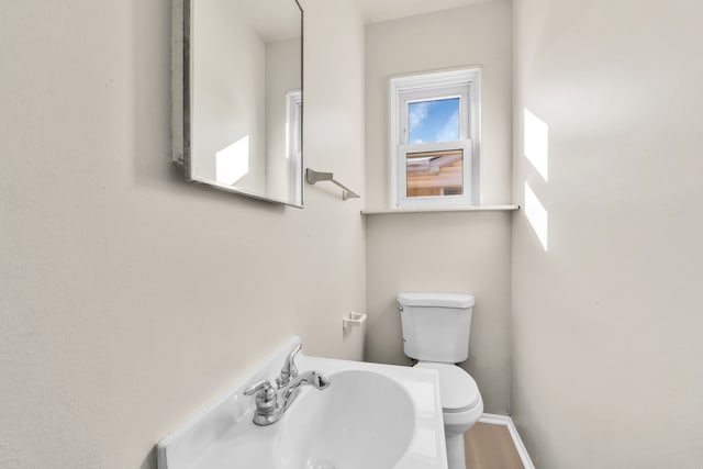 bathroom featuring toilet, baseboards, a sink, and wood finished floors