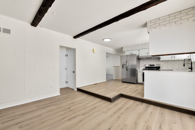 kitchen featuring stainless steel appliances, light countertops, visible vents, white cabinetry, and beamed ceiling