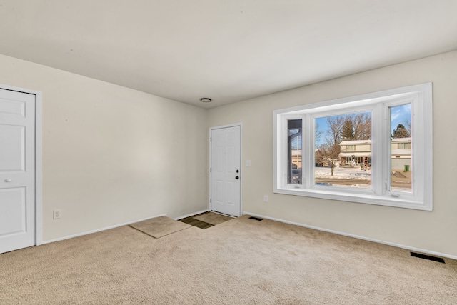 empty room with baseboards, visible vents, and light colored carpet