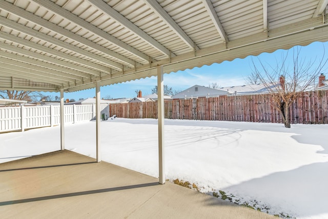 snow covered patio with a fenced backyard