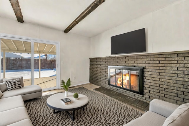 living room with a brick fireplace, beamed ceiling, and wood finished floors