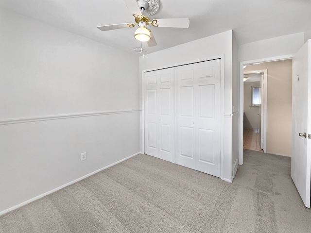 unfurnished bedroom with ceiling fan, light carpet, and a closet