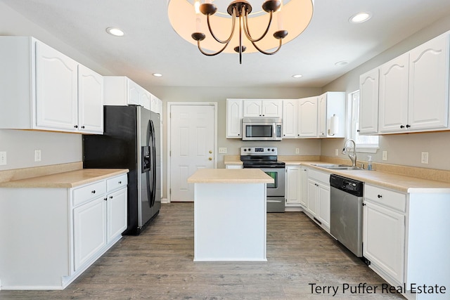 kitchen featuring sink, a kitchen island, stainless steel appliances, white cabinets, and hanging light fixtures