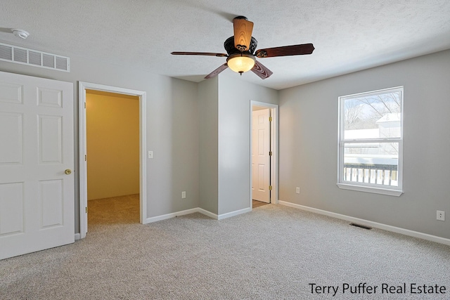 unfurnished bedroom featuring a textured ceiling, light carpet, and ceiling fan