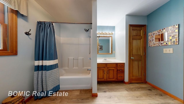 bathroom featuring baseboards, wood finished floors, shower / tub combo with curtain, and vanity
