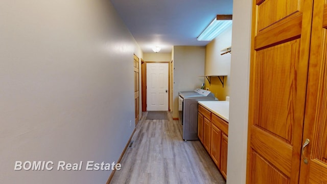 washroom featuring cabinet space, baseboards, washer and clothes dryer, and light wood finished floors