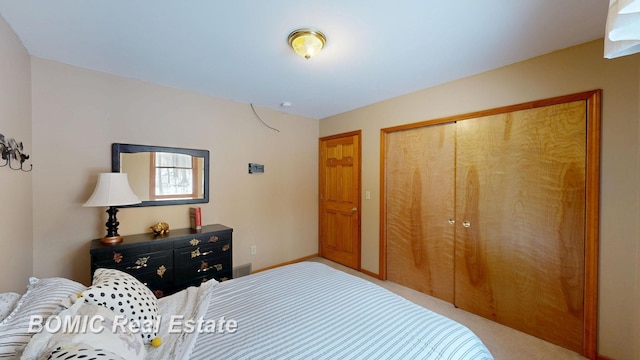 bedroom with a closet, light carpet, and baseboards