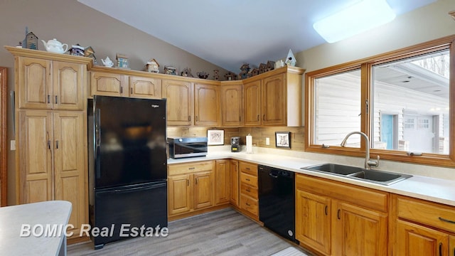kitchen featuring lofted ceiling, light countertops, a sink, and black appliances