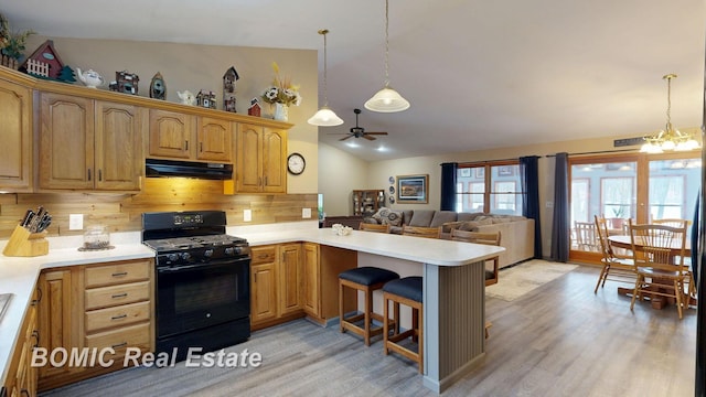kitchen featuring light countertops, hanging light fixtures, open floor plan, black gas stove, and under cabinet range hood